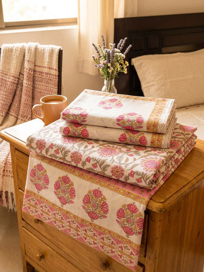 Pink floral bedsheet from Emenaura neatly folded, showcasing a soft fabric with a vibrant floral pattern.