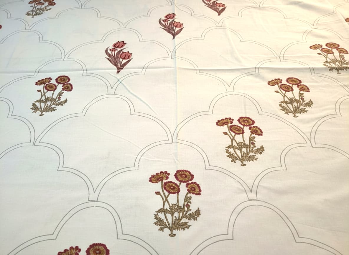 Emenaura festive cotton bedsheet set with one hand-block printed bedsheet and two embroidered cushion covers on a bed.