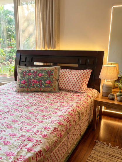 Close-up of a Rosy Bloom bedsheet by Emenaura with matching pillow covers in a cozy, well-lit bedroom setting.