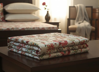 Folded hand-block printed cotton bedsheets from Emenaura's The Festive Home collection, showcasing intricate floral patterns.