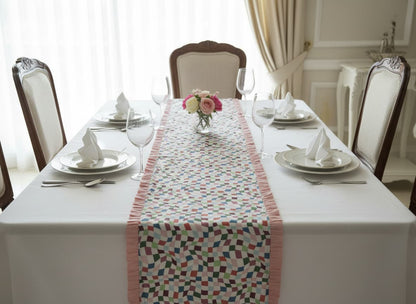 Emenaura pastel table runner on a bed with percale bedsheets, showcasing elegant home decor for festive occasions.