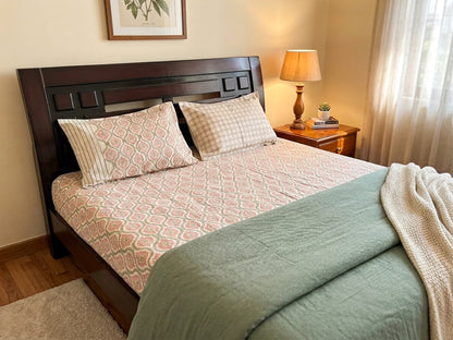 Emenaura blush cotton bedsheet set with geometric pattern, spread out on a bed, showcasing soft fabric and stylish design.