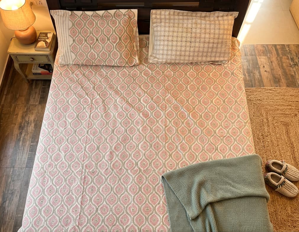 Upper view of Emenaura blush geometric cotton bedsheet set with matching pillowcases on a bed.