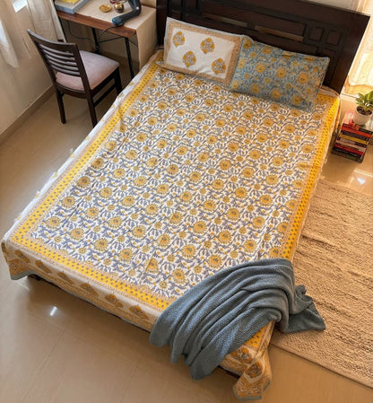 Sunlit Heritage floral cotton bedsheet by Emenaura, showing a vibrant, sunlit floral pattern on soft white cotton fabric.